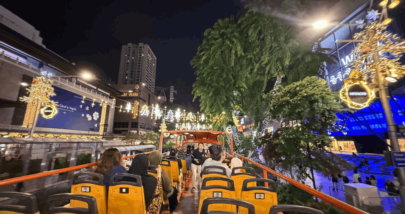 Passengers on an FunVee open-top bus tour enjoying the view of the dazzling Orchard Road Christmas lights and festive decorations at night.