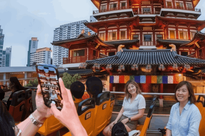 Tourists enjoying the breezy, elevated views of Chinatown’s festive lights and historic buildings from their seats on an open-top double-decker bus.