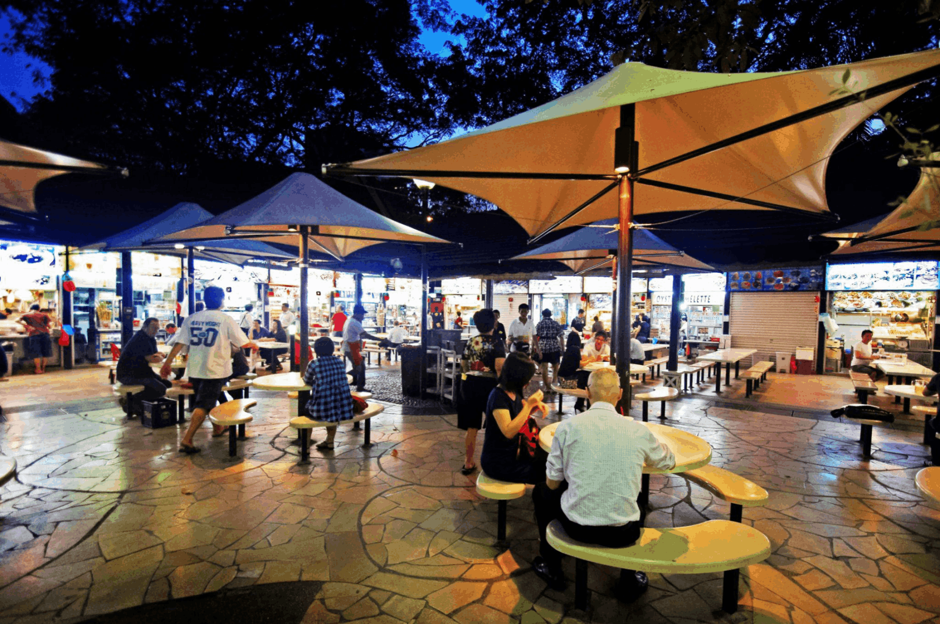 Food Centre in the evening with diners and local food stalls, a casual supper spot for visitors looking for affordable food in Singapore.