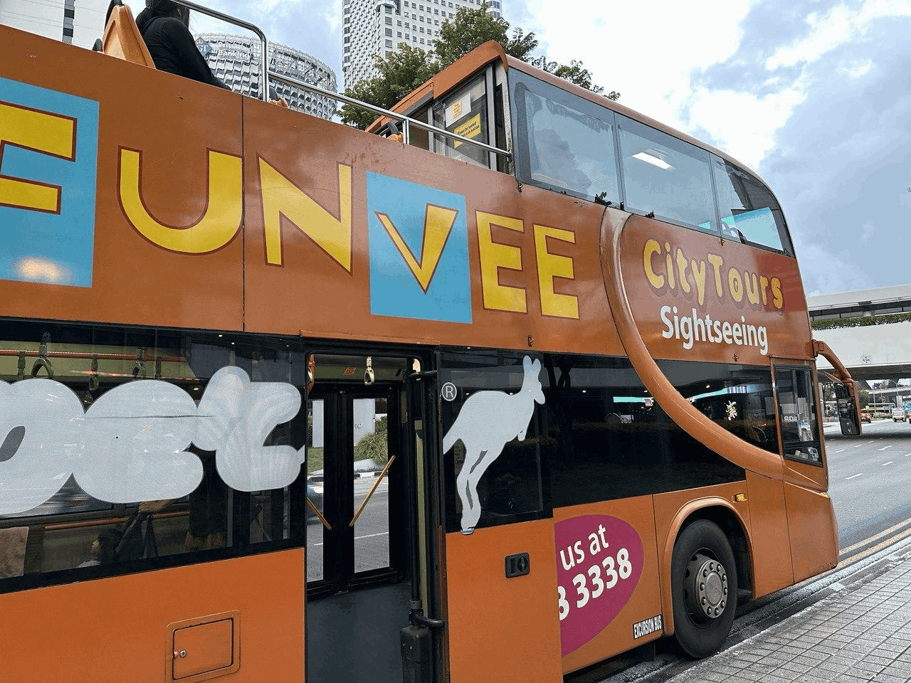 A bright orange FunVee open-top sightseeing bus parked in Singapore.