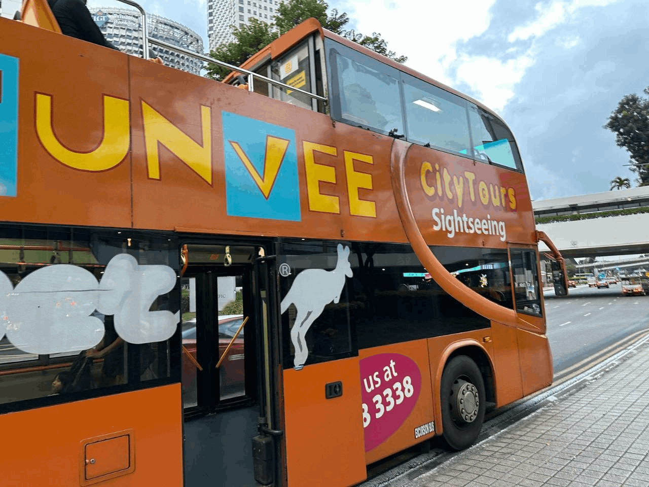 FunVee City Tours orange open-top double-decker sightseeing bus parked along a Singapore street, ready to take passengers on a city sightseeing tour.