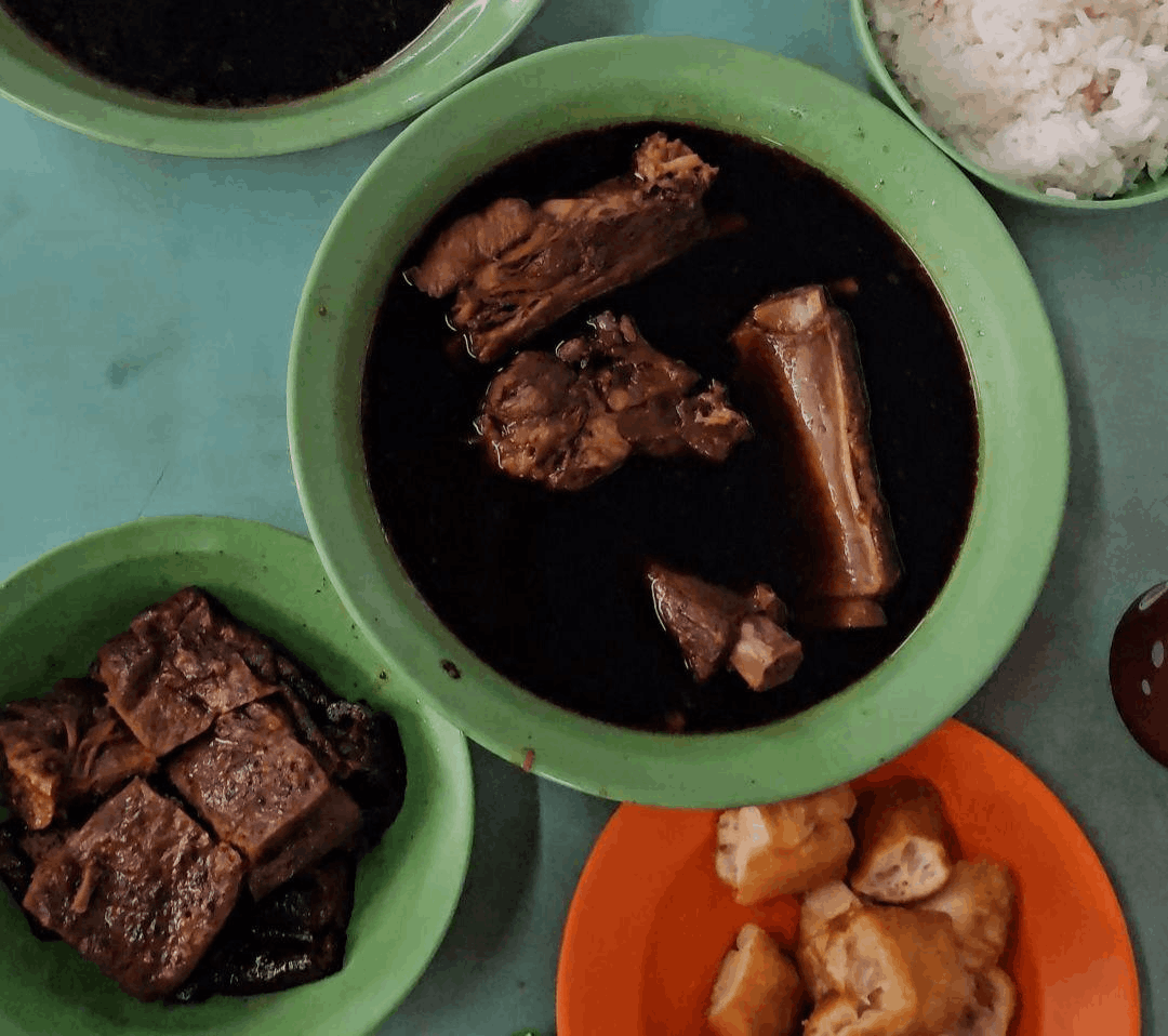 A traditional bowl of Bak Kut Teh at Hong Lim Food Centre in Singapore, featuring tender pork ribs in a rich black herbal soup served with rice and crispy you tiao.