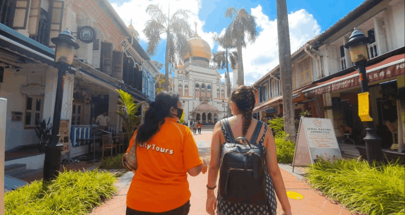 City Tours guide bringing a visitor through Kampong Glam towards Sultan Mosque during an SG Culture Pass heritage walking tour in Singapore.