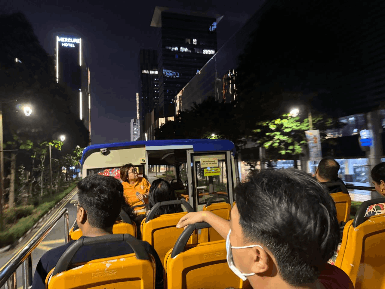 Travellers enjoying the Singapore City Lights Open-Top Night Bus Tour, a scenic evening sightseeing experience through the city.