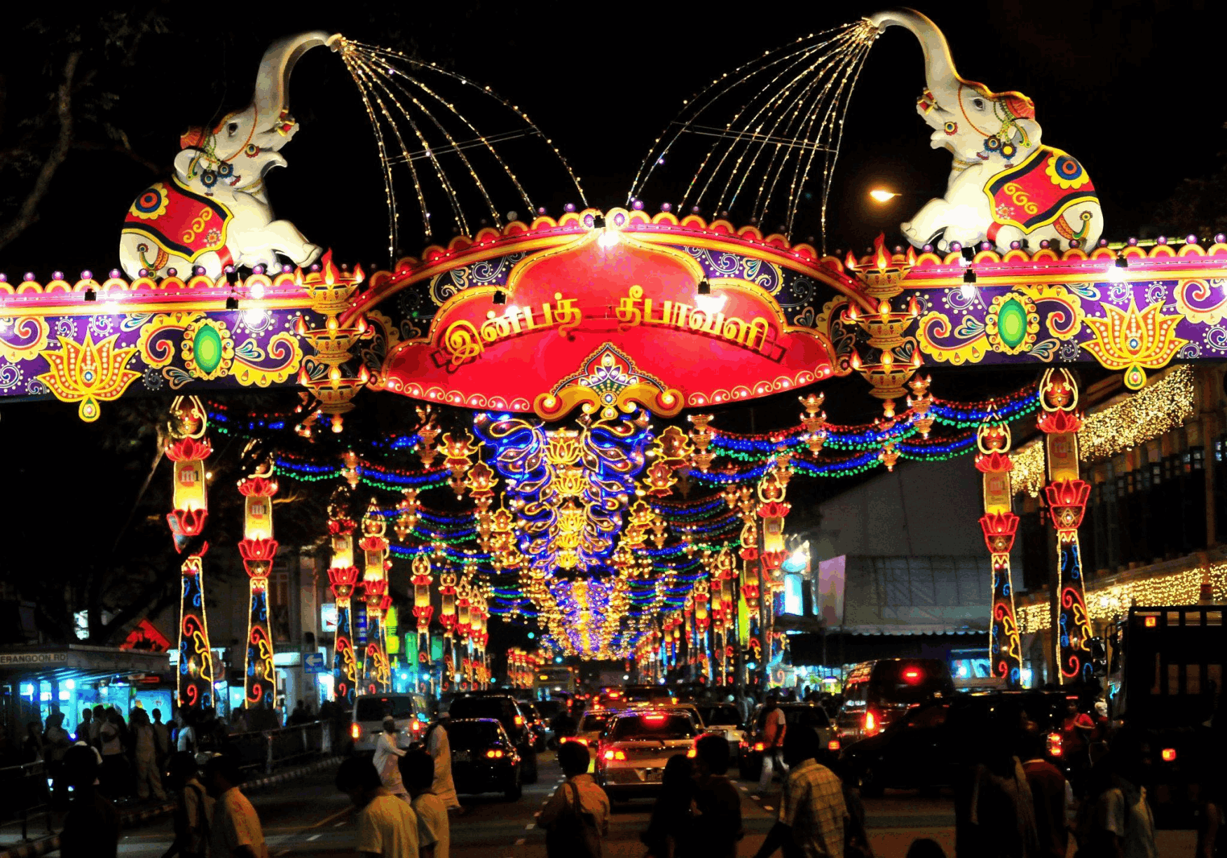 The stunning Deepavali light-up in Little India, Singapore, with a grand, colorful archway featuring illuminated elephants over a bustling street at night.