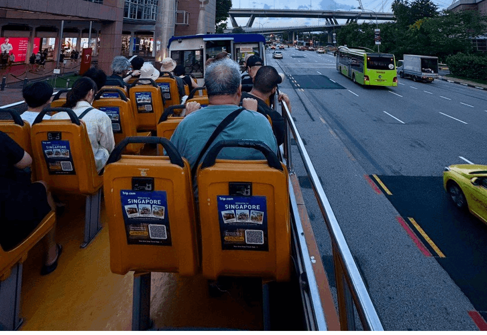 Passengers enjoying an open-top sightseeing bus tour in Singapore