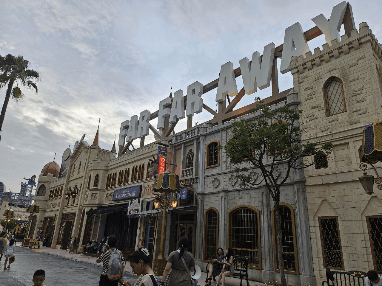 Visitors walking through the Far Far Away zone at Universal Studios Singapore, with the iconic castle and sign from the Shrek movies towering above.